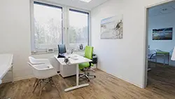 Behandlungsraum mit Schreibtisch und Stühlen